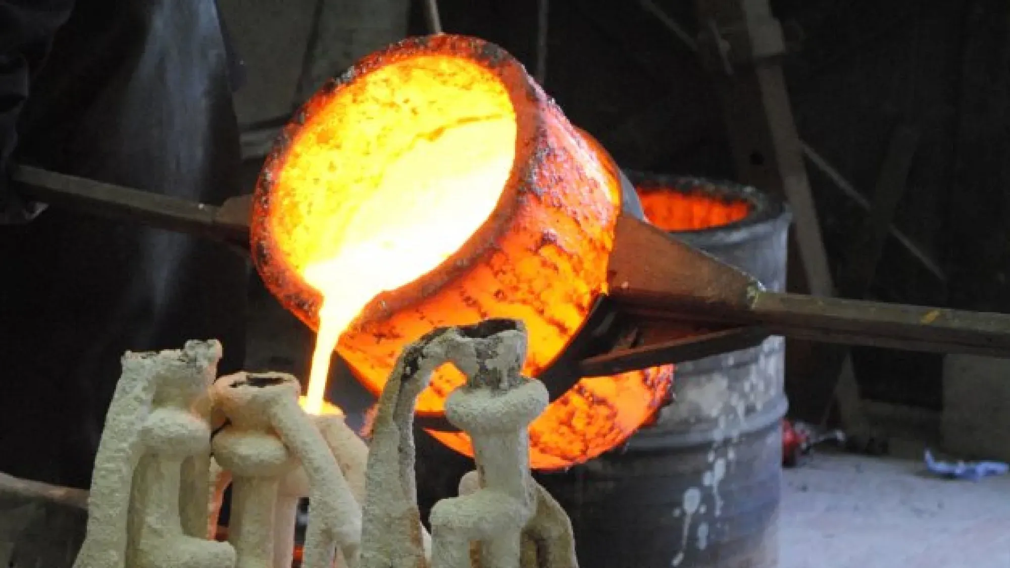 Bronze casting process showing molten metal being poured into a mold